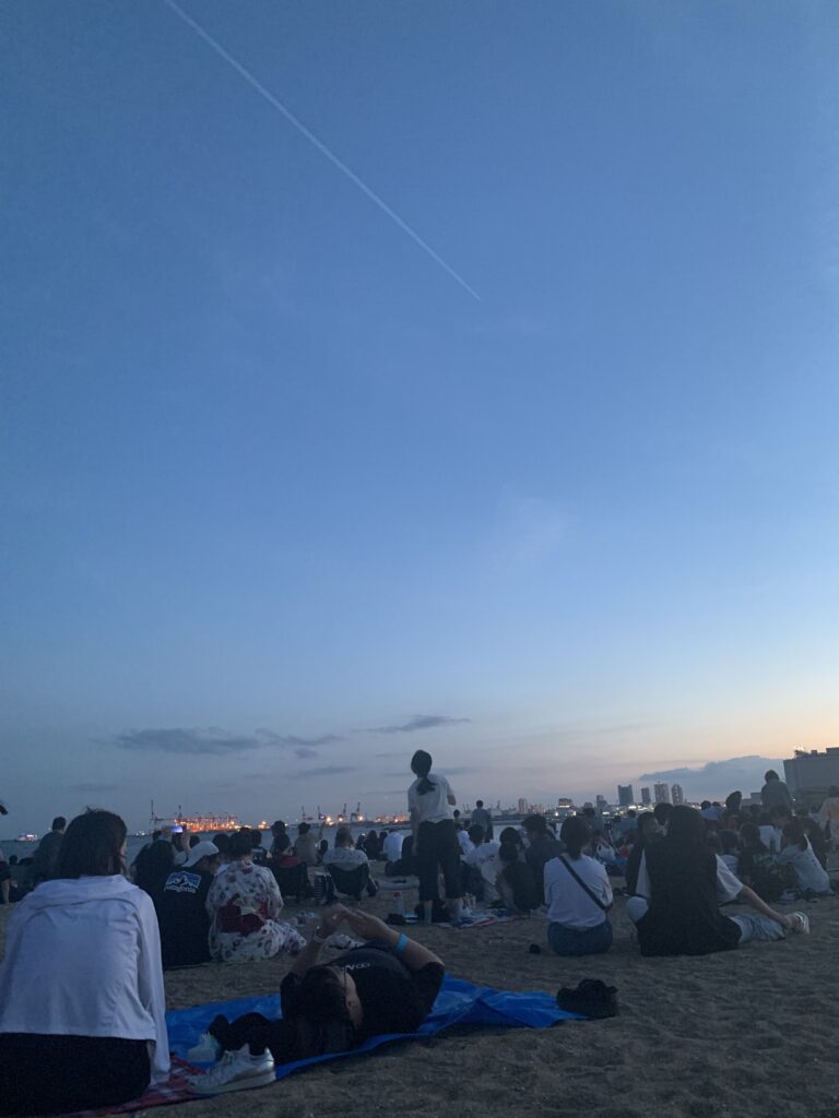 芦屋サマーカーニバル 夕暮れの砂浜に人が座っている